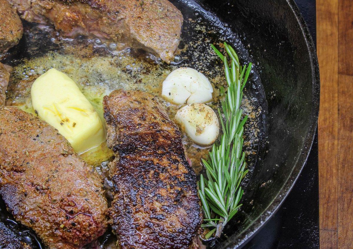 Reduce the heat to medium, then add half the butter, all the garlic, and fresh rosemary to the skillet.