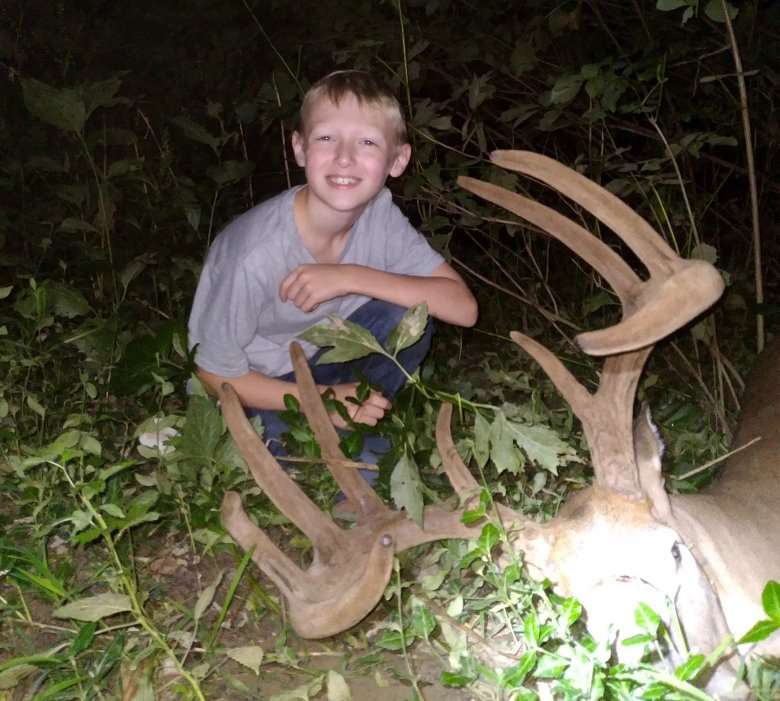 Ashton posing with his dad's buck after the pair tracked and found the deer. Image by Joe Lacefield
