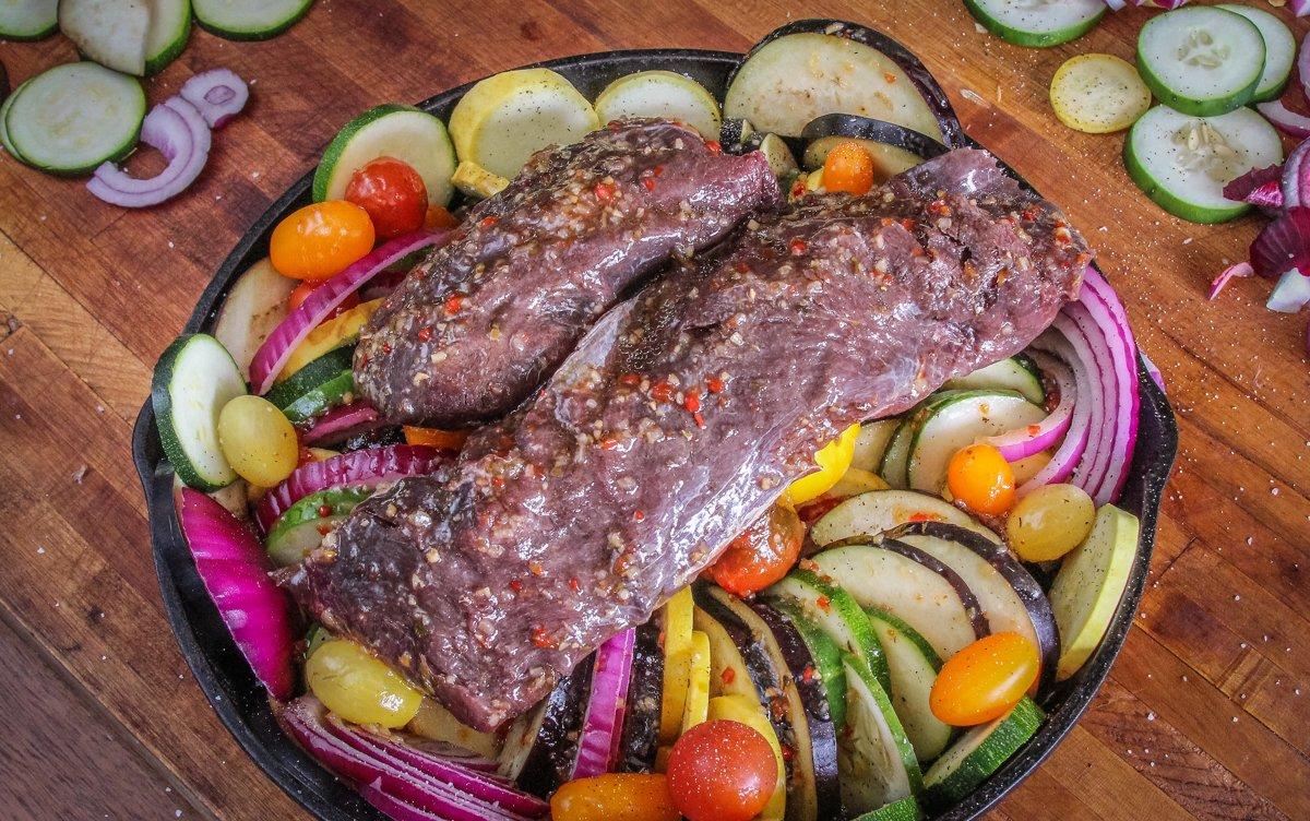 Marinate the backstrap, then place it on top of the vegetables to grill.