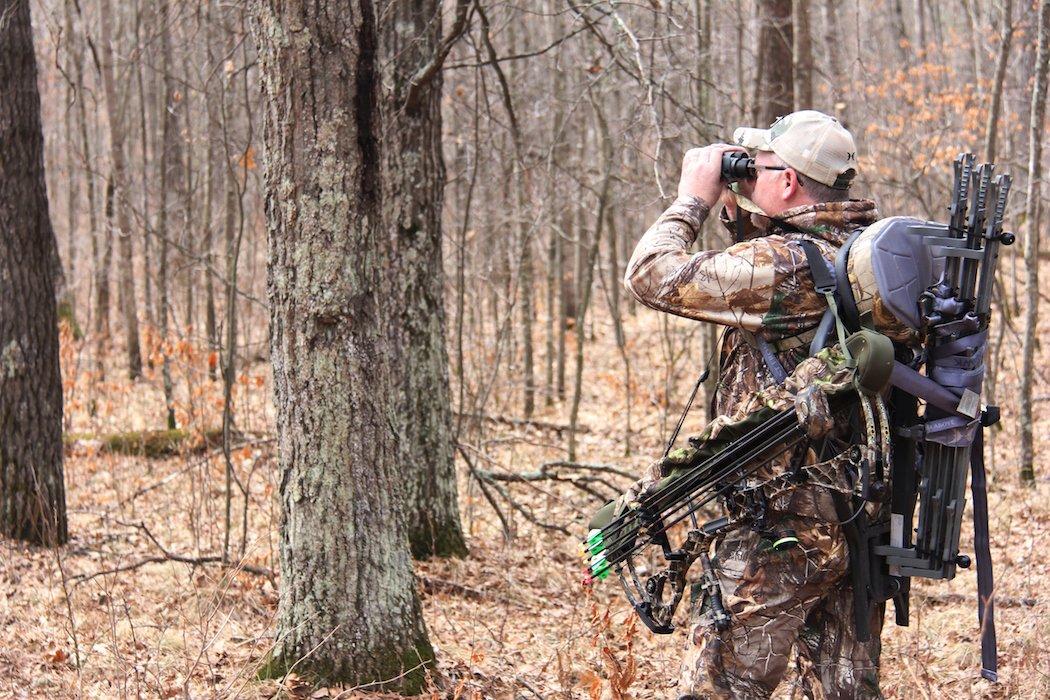 Photo of a camouflaged forest sniper hunter with crossbow posing