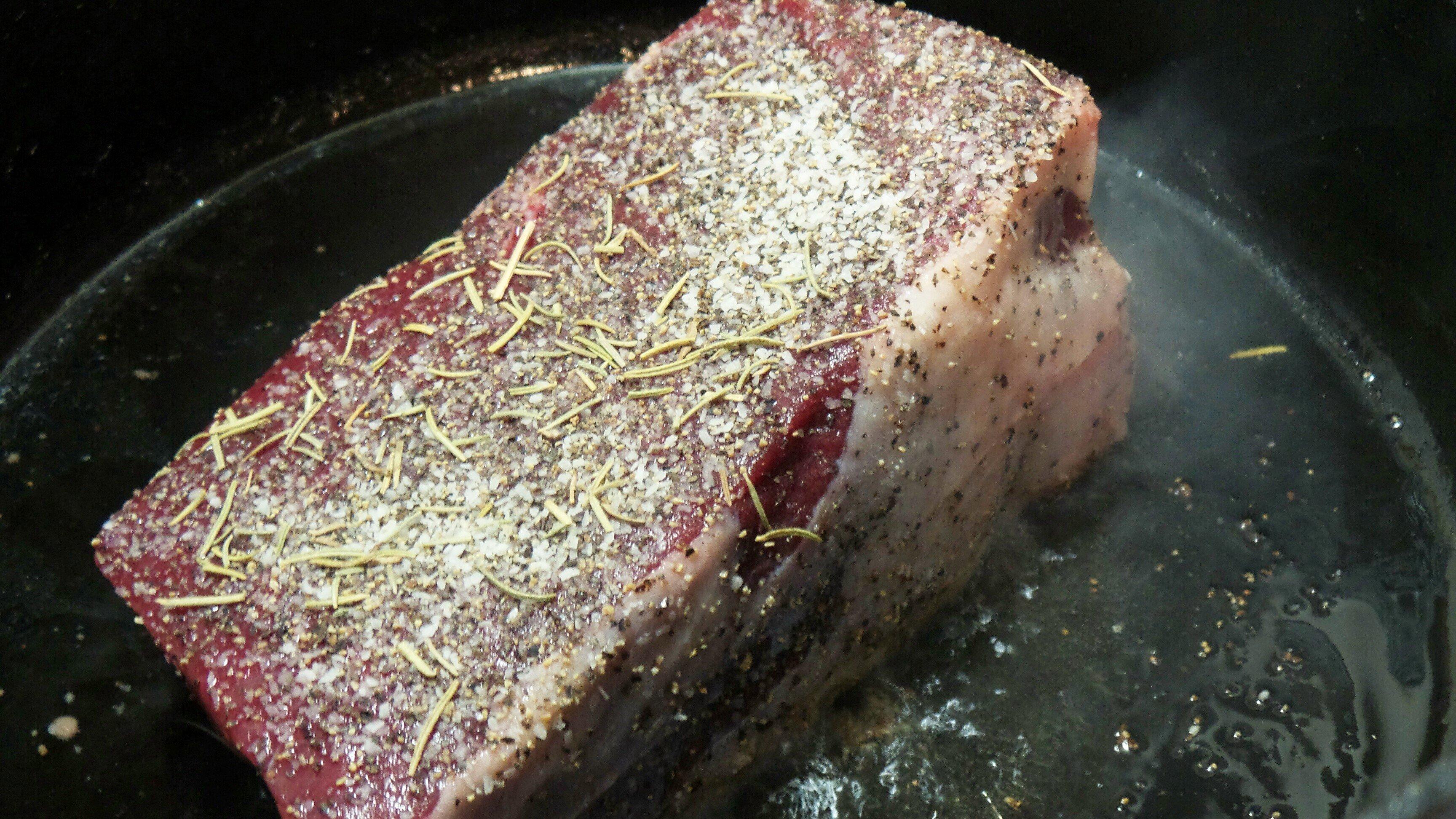 Sear the seasoned roast in hot oil.