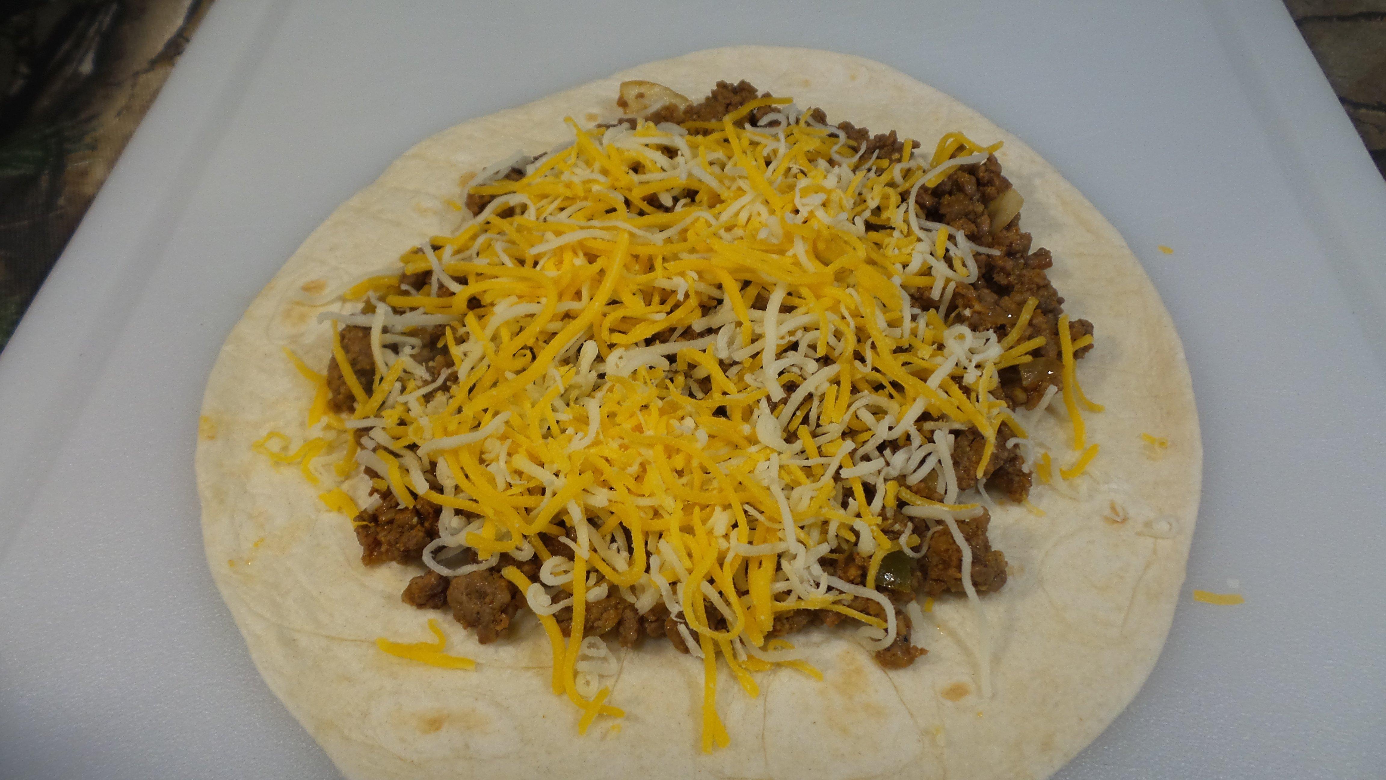 Top the tortilla with the ground meat mixture and cheese.