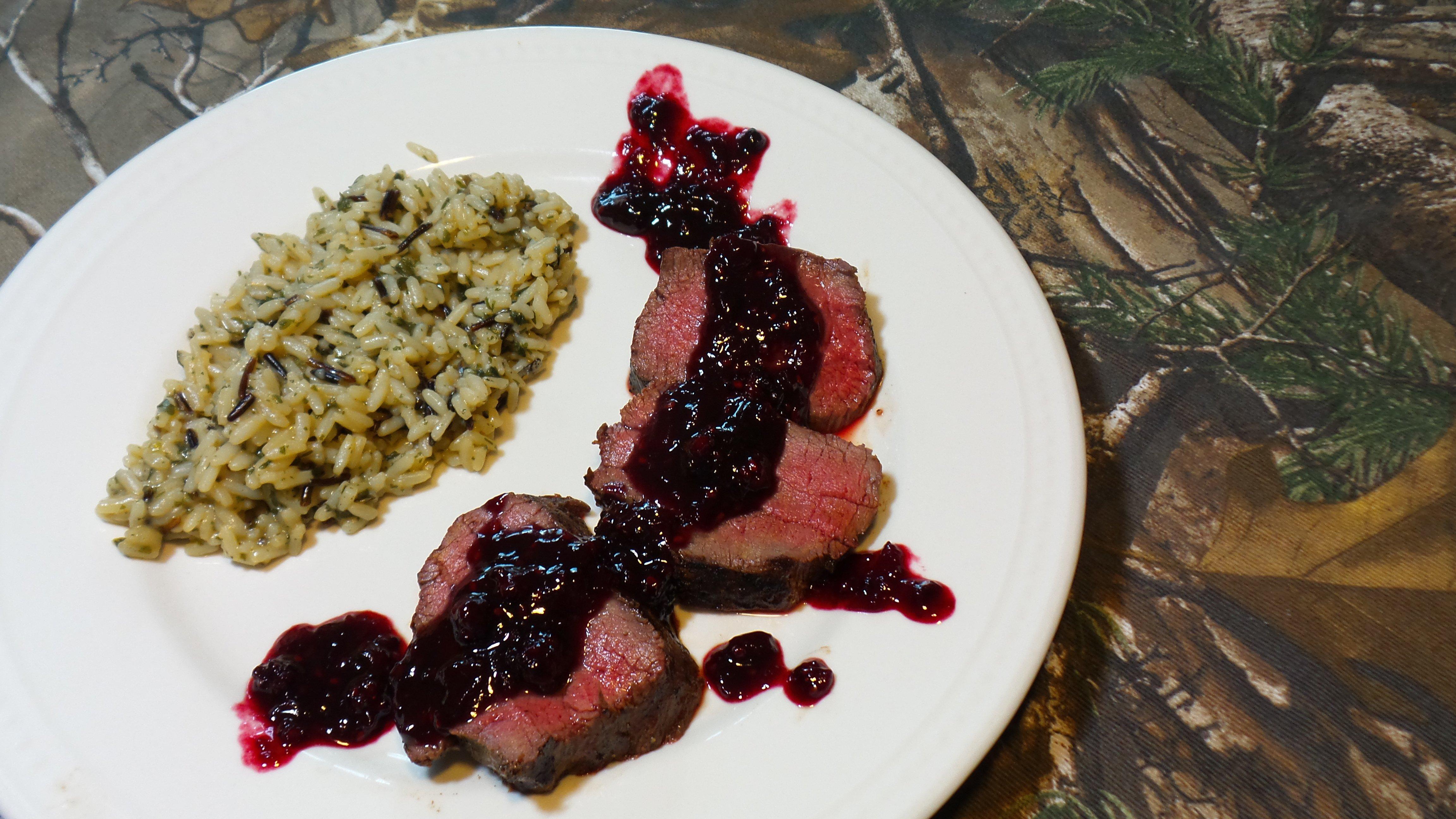 Plate the venison medallions and spoon over the black and blue bourbon sauce.