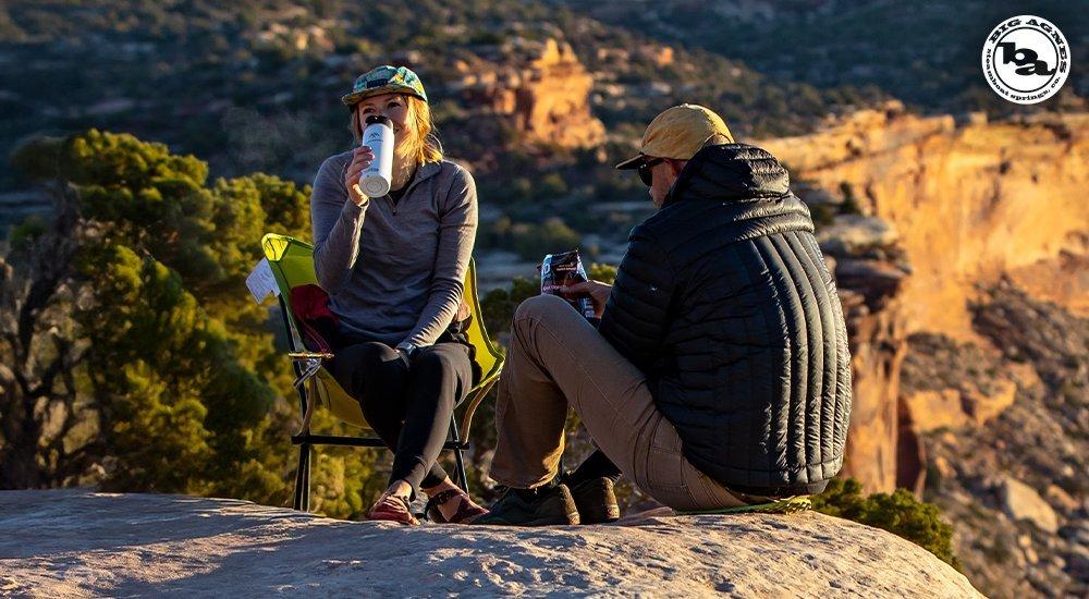 A couple relaxes outside together with a view over a cliff