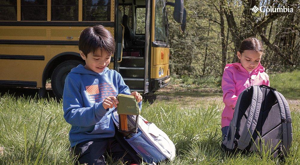 two kids sitting with backpacks