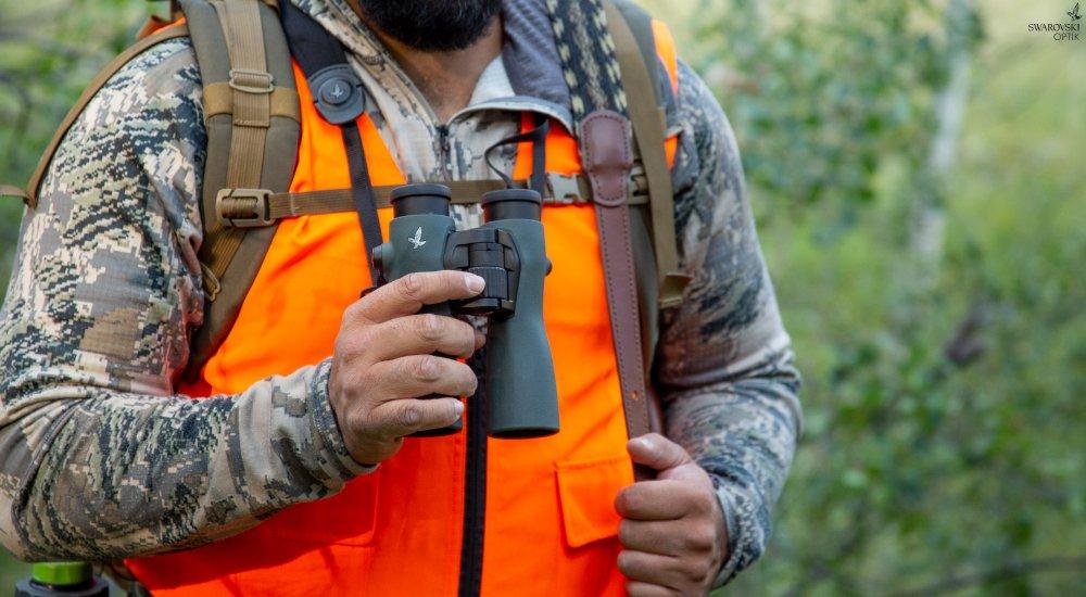 a man holding a pair of binoculars when hunting