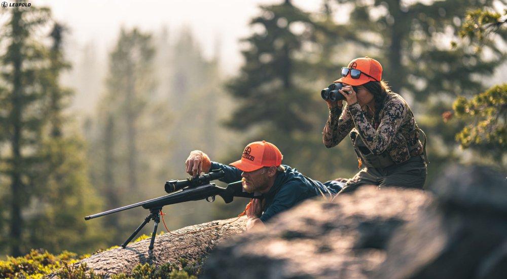 two hunters out hunting with a rifle scope and a pair of binoculars