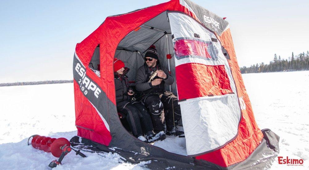 a father and son sitting in a flip over ice shelter on the ice