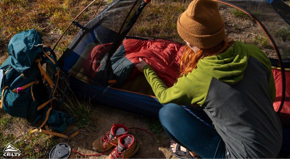 a woman setting up her sleeping bag in her tent