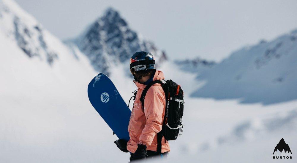 a man carrying up his snowboard on a hill