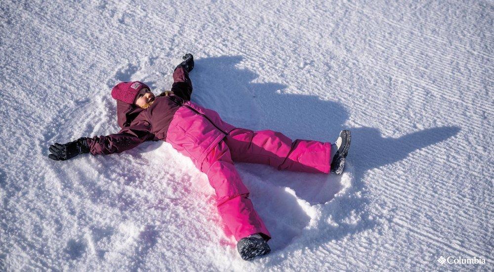A girl makes a snow angel wearing Columbia snow gear