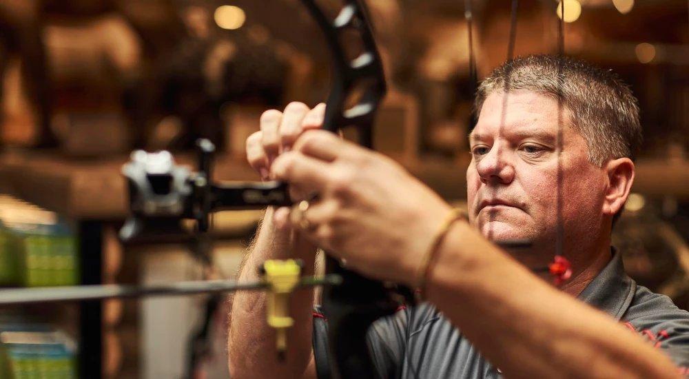 a SCHEELS associate working on a bow in store