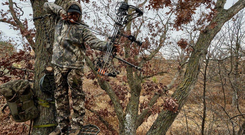a hunter using a compound bow in the treestand