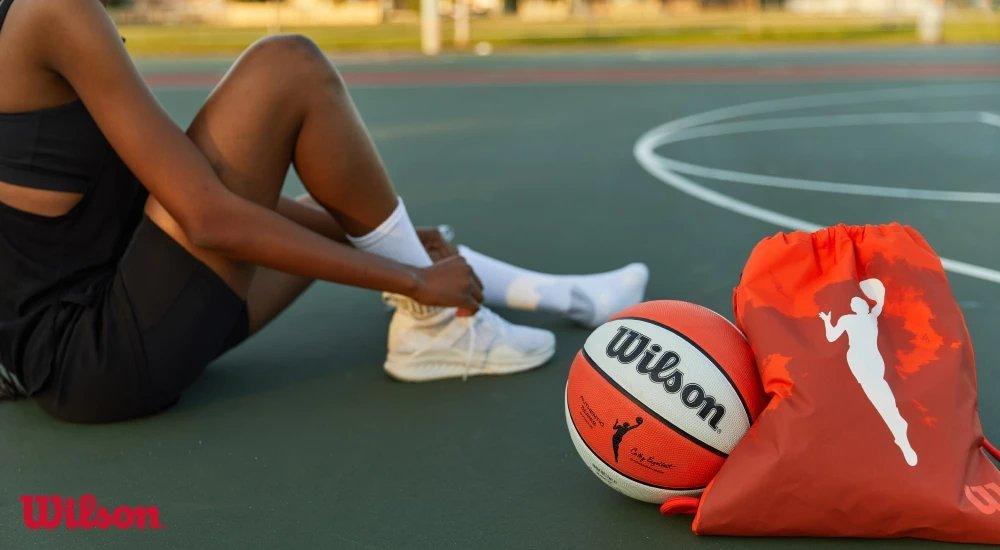 a person tying her basketball shoes on a basketball court