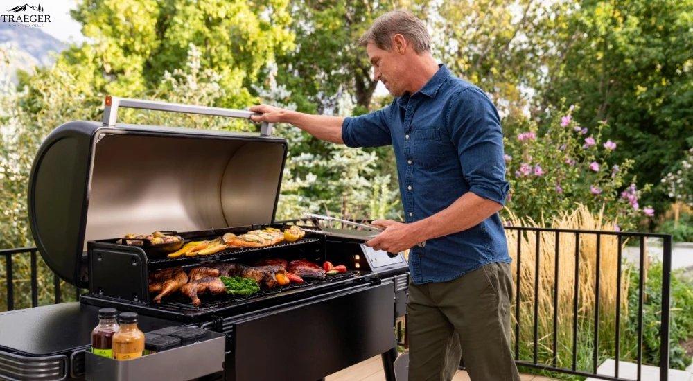 a man opening a Traeger grill outsie on his deck