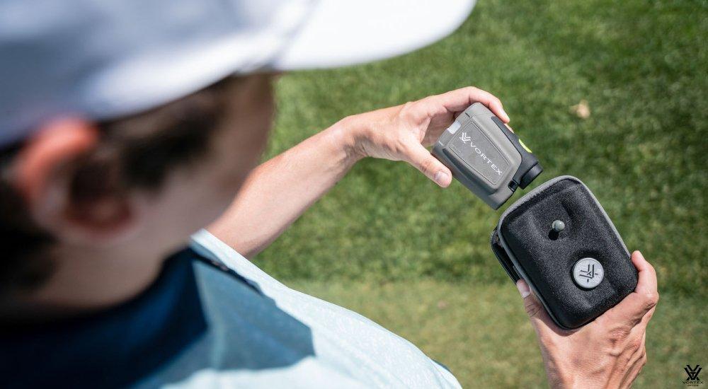 a male pulling out a Vortex golf rangefinder from the case
