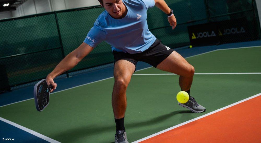 a player using a JOOLA pickleball paddle to hit a pickleball in a game