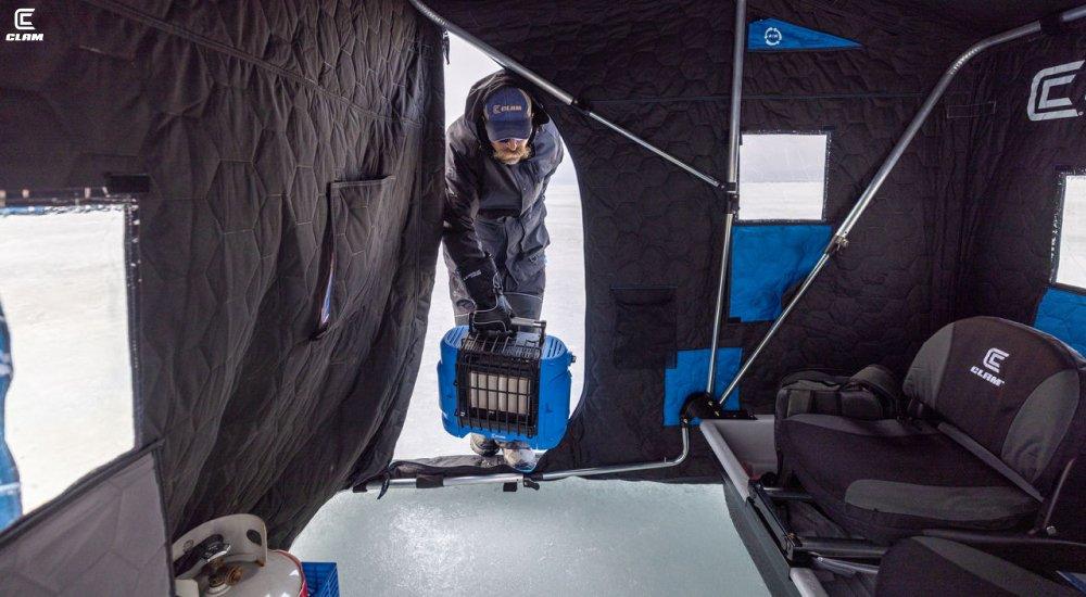 a man putting an ice fishing heater into his ice house