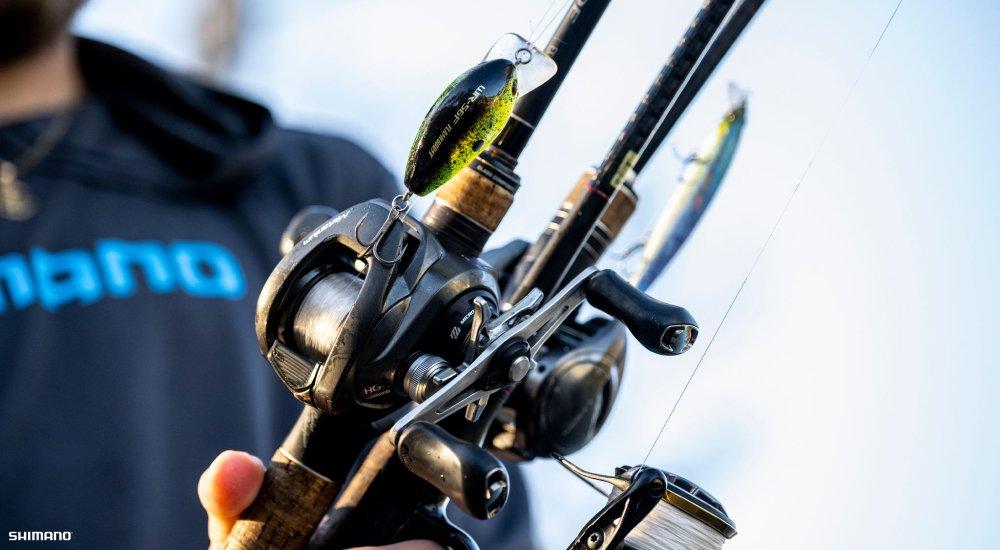 a man holding up two rods with baitcaster reels