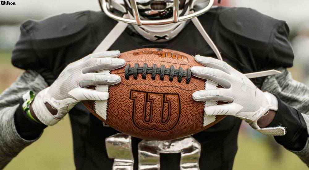 a football player holding a Wilson football before a game