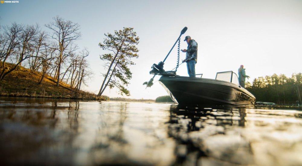 an angler standing on a boat with the trolling motor out of the water
