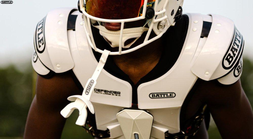 a football players wearing football shoulder pads and a helmet in practice