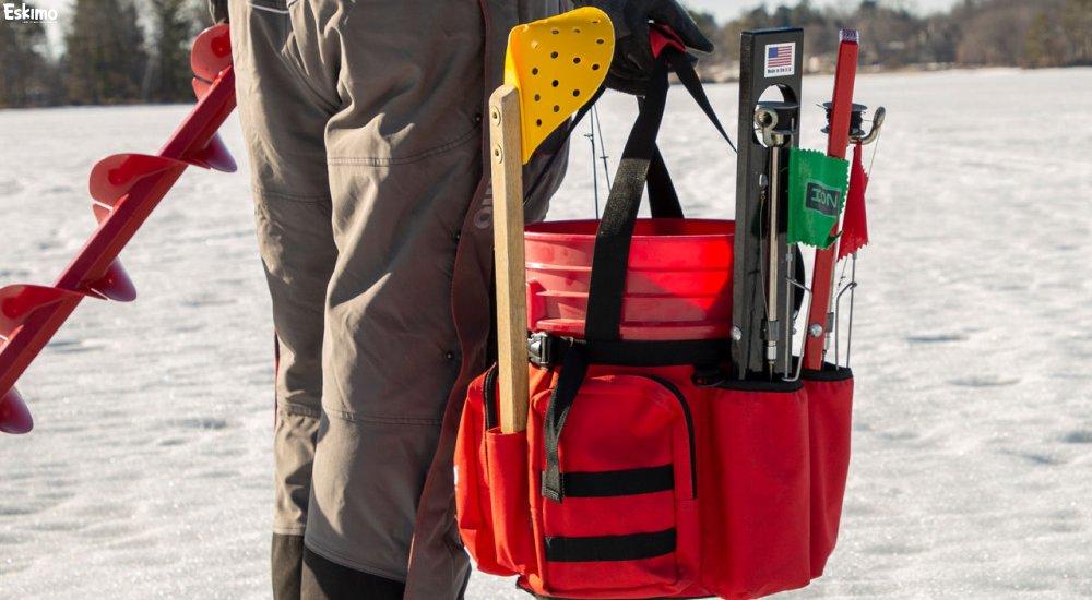 an ice angler carrying a bunch of ice fishing gear on the ice