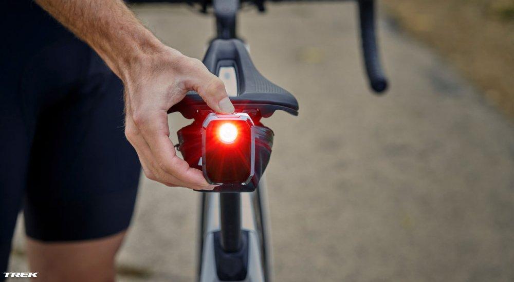 a person turning on a bike light at the rear of the bike