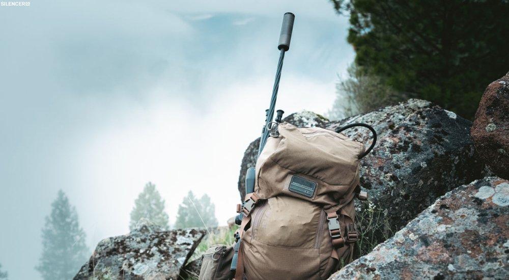 a muzzle device on the end of a gun while someone is out hunting in the backcountry