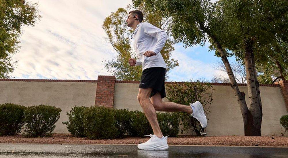 Wyatt running outdoors on pavement in a pair of HOKA running shoes