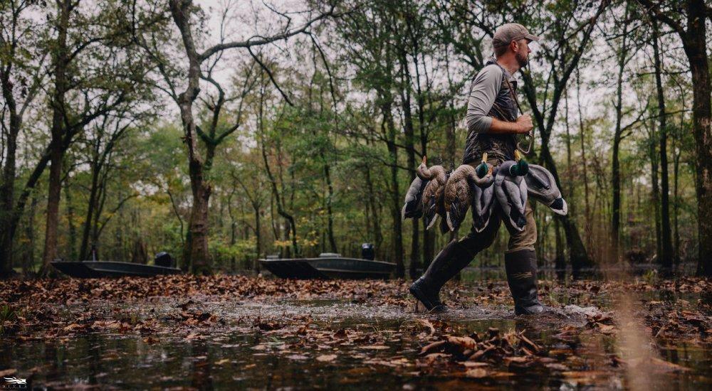 a hunter walking through the water wearing SITKA hunting boots