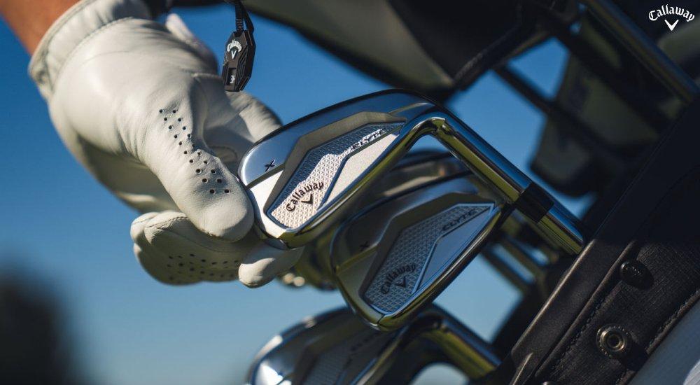a golfer reaching for an iron in his golf bag