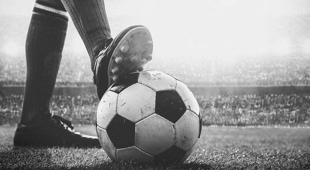 black and white image of soccer players cleat on a soccer ball