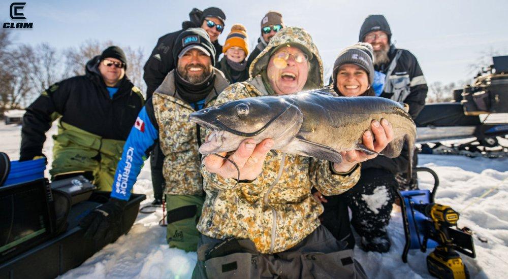 man holding a fish with a group of people behind him