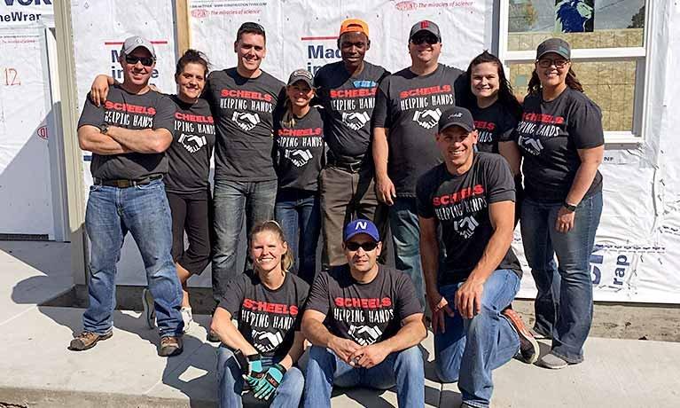 employees standing for a pictures with scheels helping hands t-shirts