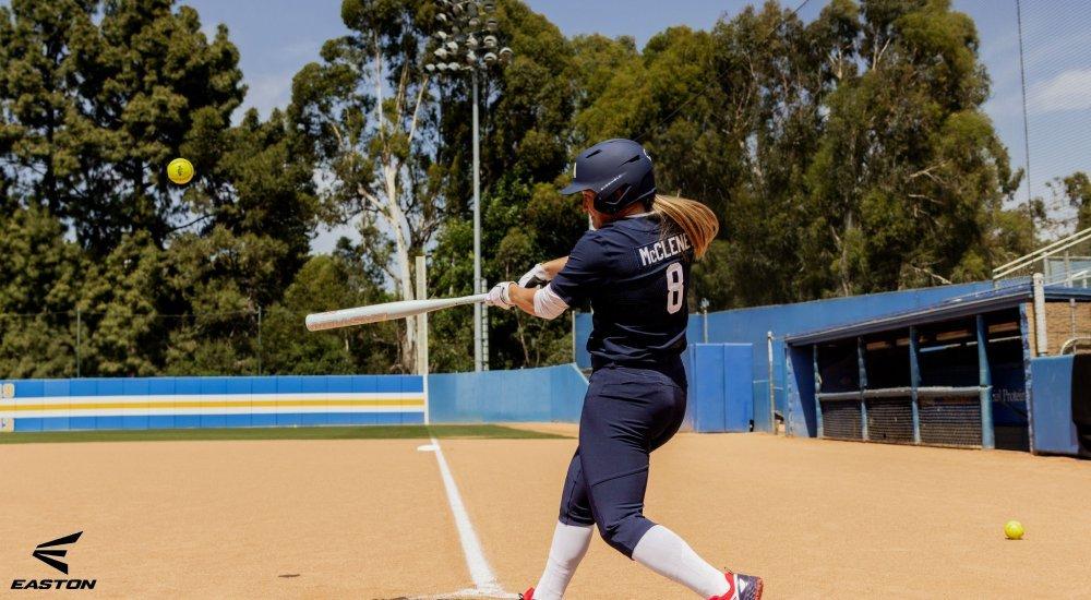 softball player hitting softball with bat