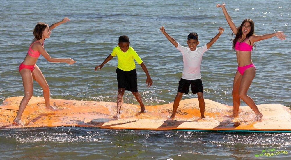 four kids standing on a lily aqua pad