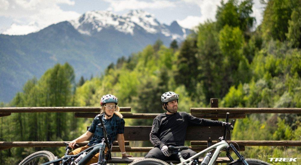 two cyclists sitting on a bench wearing bike helmets