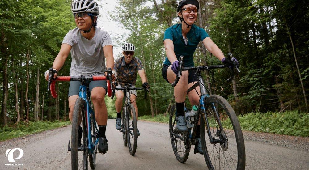 three people riding bikes on a gravel road