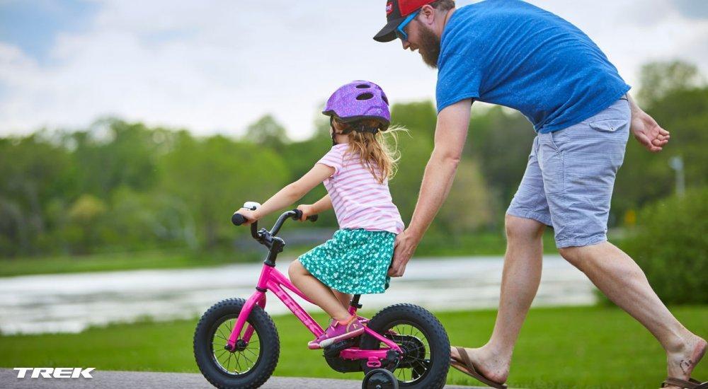 adult helping kid ride a bike
