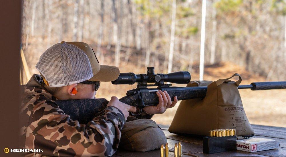 man looking through a riflescope and aiming a firearm
