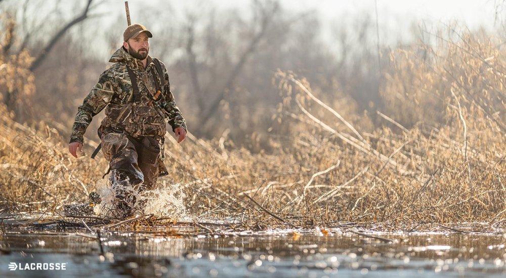 Person walking through water in camo hunting waders