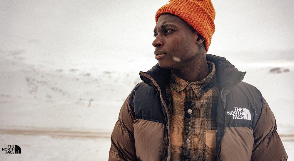Man, standing in the snow, wearing a brown puffer coat 