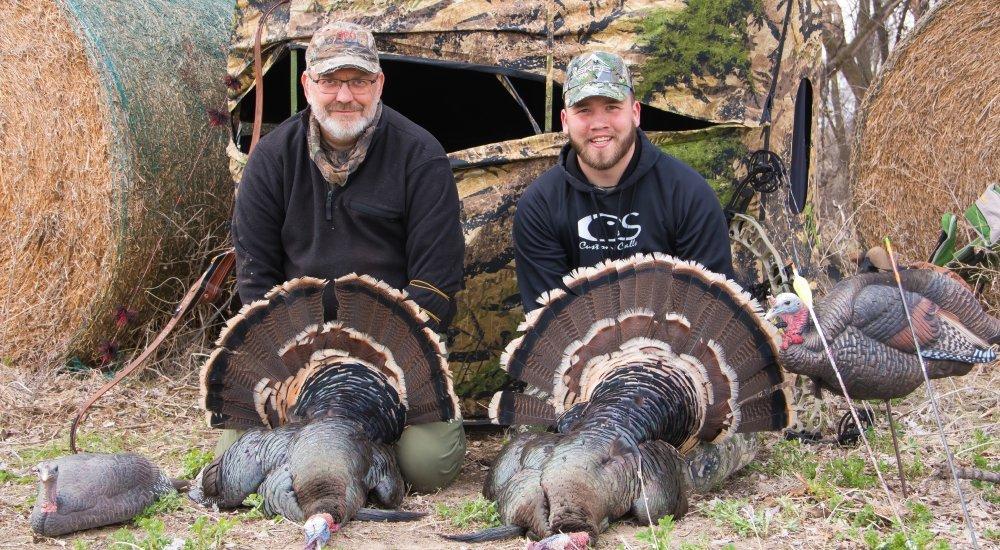 two men holding turkeys next two each other