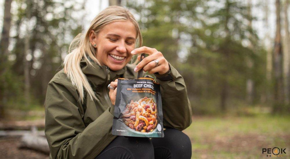 a girl eating freeze dried food at a campground