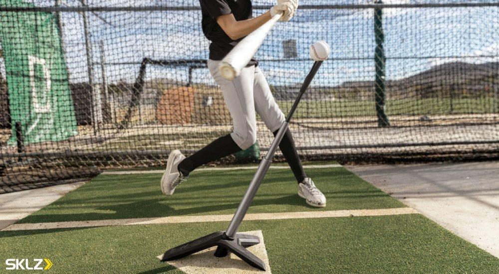 baseball player swinging at a baseball on a tee