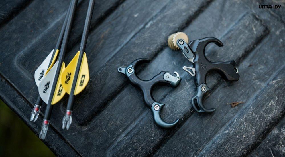 2 bow releases next to some arrows