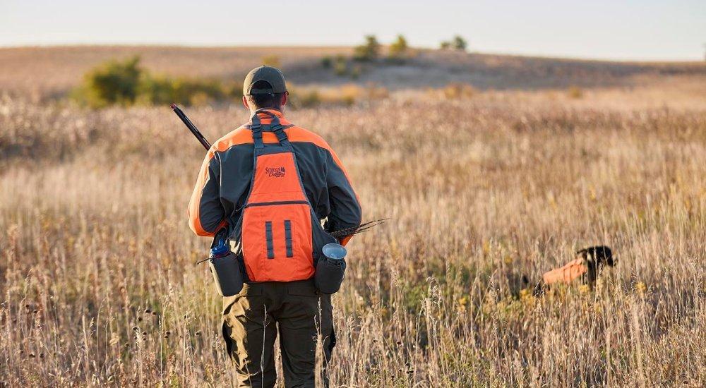 An upland hunter wearing a Scheels Outfitters strap vest