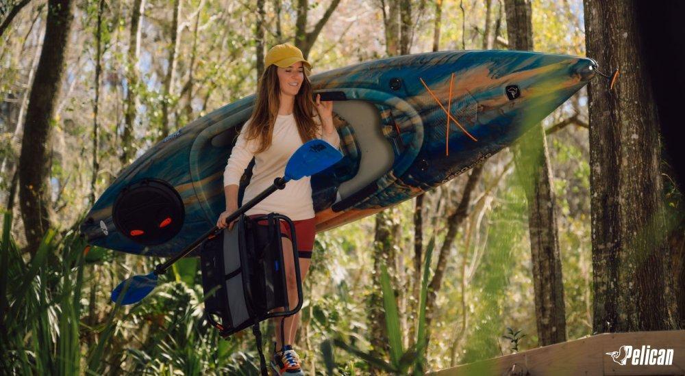 woman carrying her kayak and accessories