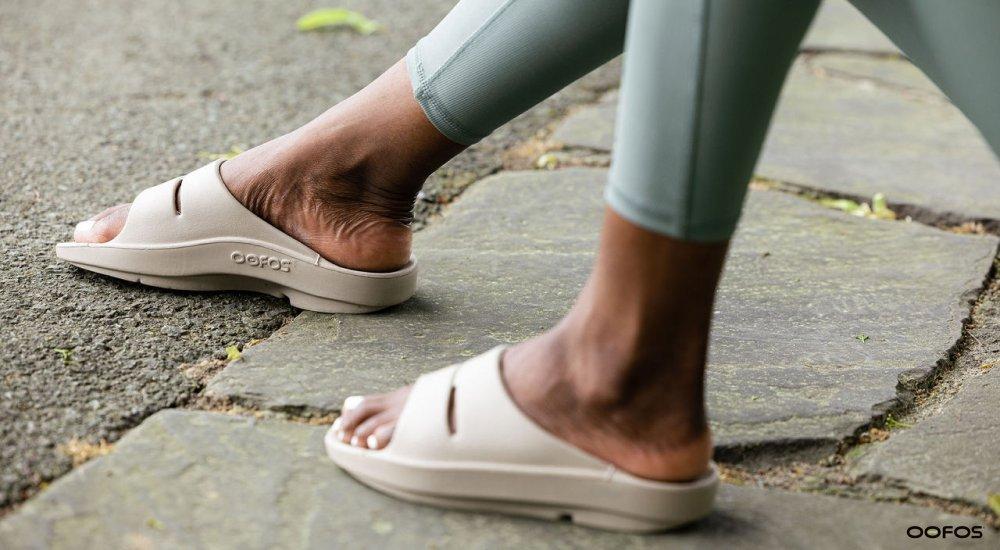 Person wearing tan-colored OOFOS recovery slides